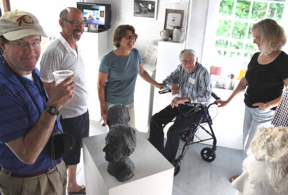 Sculptor Alex Bauer, 92 and a Cooperstown resident for six years, was honored this evening at the opening of the Smithy Pioneer Gallery's first show of the season, "On Closer Inspection" At left is his son, Dr. Mike Bauer, and to the sculptor's right is his daughter Jane. Bauer's sculpture, and the works of six artists, will be on view through June 29. (Jim Kevlin/allotsego.com)