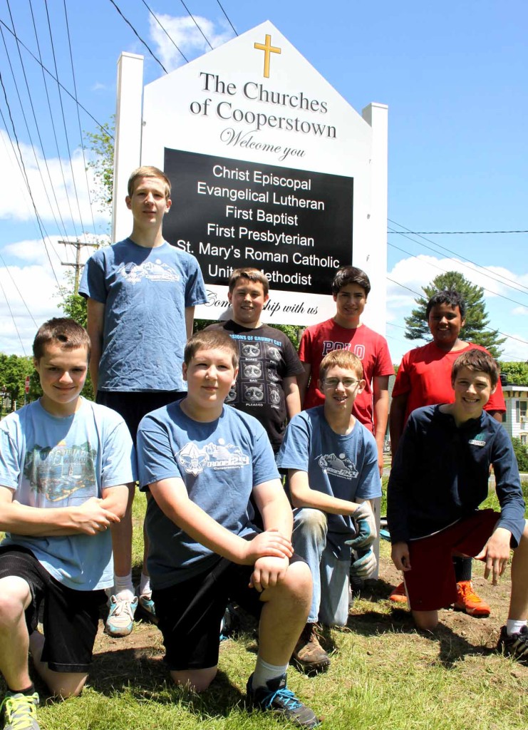 Eagle Scout candidate Charles Gannon, standing at left, obtained the help of his fellow Troop 1254 scouts for signs at the two Route 28 entrances to the village welcoming visitors to Cooperstown's churches.   Others standing, from left, are Tim Walker, Daniel Rudloff and Nathaniel Miller.  Front row, from left, are Matthew Hulse,  Eric Deysenroth, Leo Gannon and Steve Ratliff.  Also assisting were Josh Briggs and Anthony Birch.  (Jim Kevlin/allotsego.com)