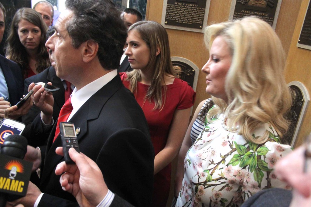 Governor Cuomo answers reporters' questions after arriving at the Hall of Plaque from his downstate nomination for a second term, just missing President Obama.  At right is Sandra Lee, his companion Food Network TV host.  (Jim Kevlin/allotsego.com)