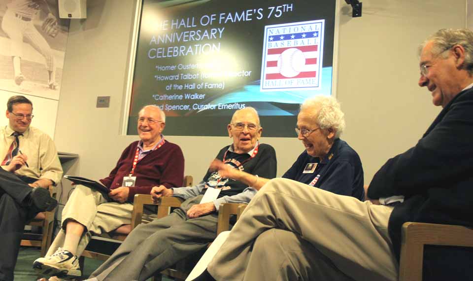 Laughter erupted when Catherine Walker recalled, a little disparagingly, the "red coats" Hall staffers used to wear.  Be careful, they were my idea, said former Hall director Howard Talbot, second from left.  The two, both of whom attended the 1930 Induction, joined Homer Osterhoudt, center, at a panel discuss in the Hall of Fame's BullpenTheater at 1 p.m. today, part of the 75th anniversary festivities.  (Jim Kevlin/allotsego.com)