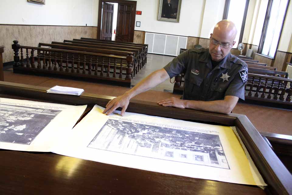 Herkimer County Deputy Sheriff George Piper reviews photos of Chester Gillette's 1906 trial this afternoon in the courtroom where it occurred.  Officials at historical sites in Herkimer, the Adirondacks and Cortland are expecting an increase in visitors this summer due to Tobias Picker's "An American Tragedy," which opens next Friday at Cooperstown's Glimmerglass Festival.  (Jim Kevlin/allotsego.com)