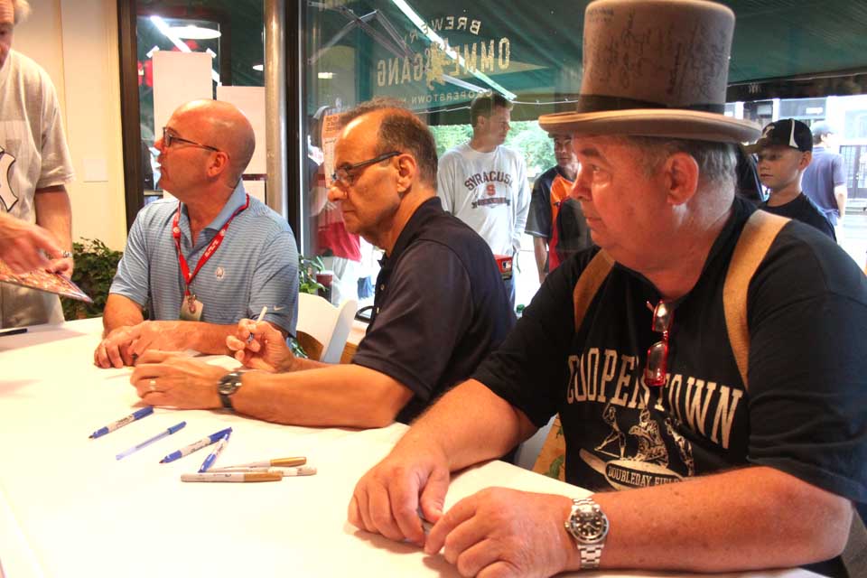 Fabled Yankee manager Joe Torre, 24 hours after his induction into the Baseball Hall of Fame, signs autographs at Ommegang's Prohibition Store on Cooperstown's Main Street at this hour.  By his side is longtime pal Ted Hargrove, who arranged the appearance.  Fans are lined up along Main at this hour waiting for the chance at an autograph.  Co-Hall of Famer Bobby  Cox is also signing.  (Jim Kevlin/allotsego.com)