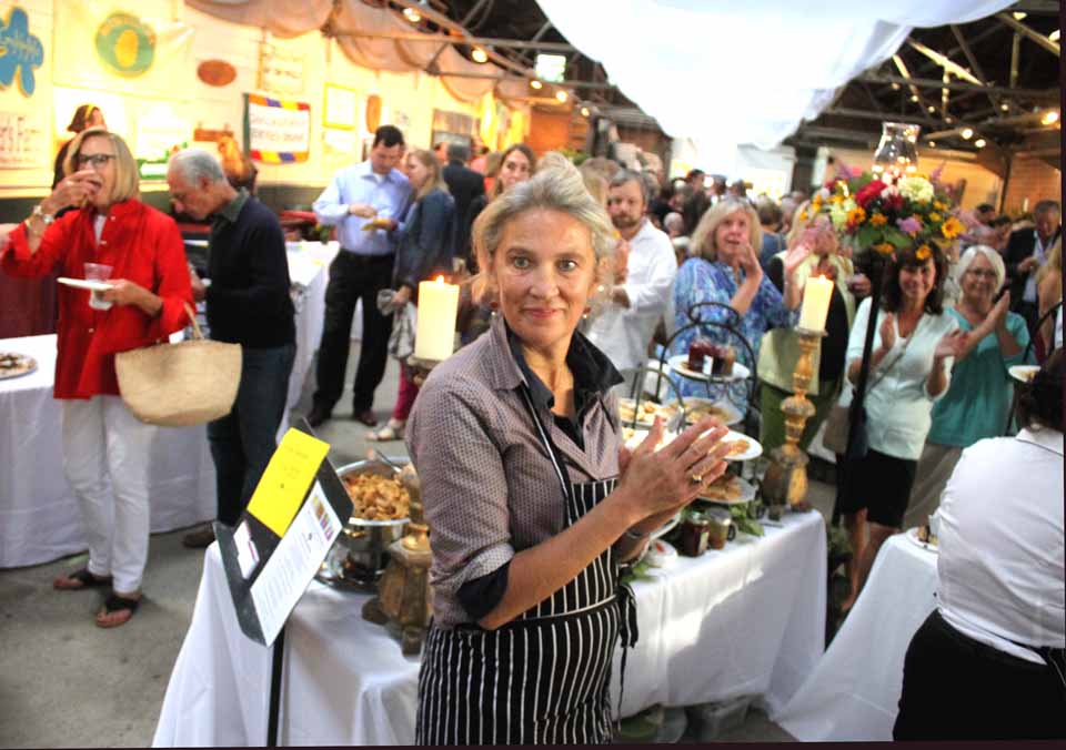Lucy Townsend of L.M. Townsend Catering and the Firehouse Market joins the applause at Otsego 2000's Ellen Pope heralds the success of her organization's second annual "Local Food, Local Spirits" celebration this evening in the Cooperstown Farmers' Market. The event, moved to the spacious venue after it sold out last year, enticed 270 revellers to pay $35 each to sample locally grown treats. The favorite vendor, per the voting of the crowd, was Origins Cafe. (Jim Kevlin/allotsego.com)