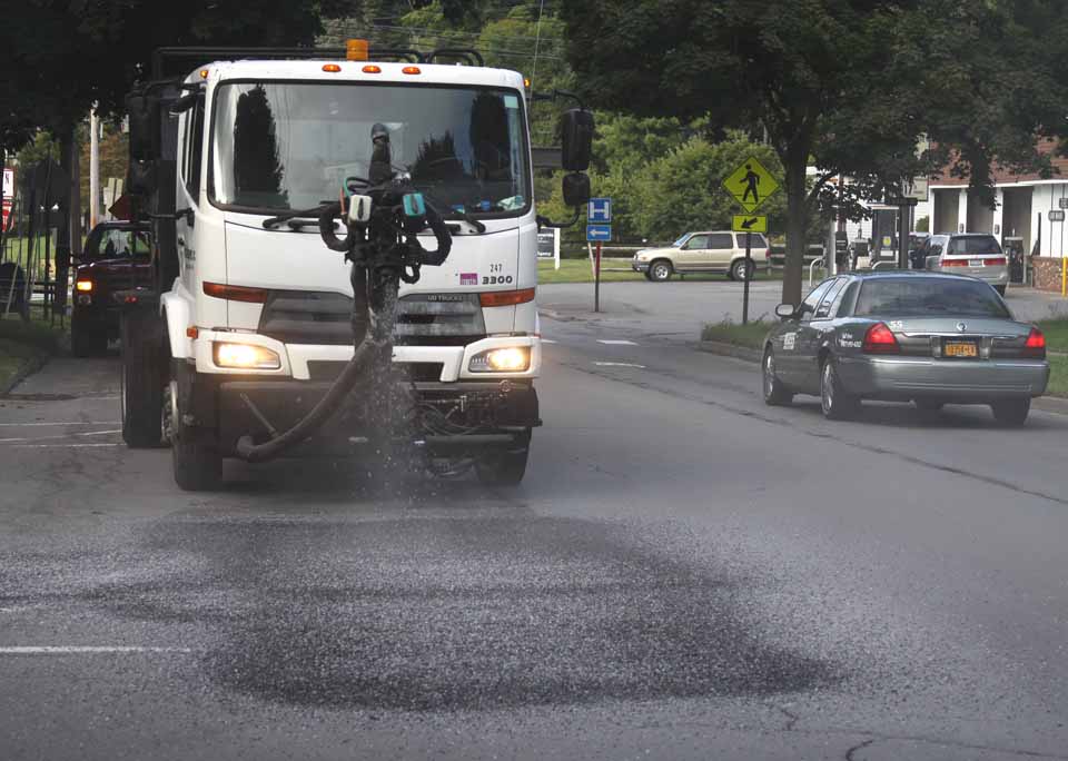 The Pothill Killers' truck sprays gravel into a refilled pothole along Cooperstown's Chestnut Street earlier this week.  (Jim Kevlin/allotsego.com)