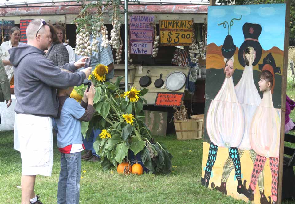 Gretchen Brown and Luna Font, 3, take time out from examining the offerings at the Susquehanna Garlic Fest, on until 5 p.m. today at Woodbull Antiques, Milford, to assume the persona of garlic cloves.  Brian Haines and Owen Brown, 7, immortalize the moment.  All are from Oneonta.  (allotsego.com)