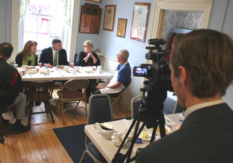 Congressman Chris Gibson, R-19, chats with Bill Glockler, a Cooperstown Rotarian and his Otsego County campaign manager in 2012, during a stop a few minutes ago at the Rotary Club's Election Day Pancake Fest at the Cooperstown Vets Club. With him are his wife, Mary Jo, and his Cooperstown aide, former mayor Carol B. Waller. WUTR's Corey Fisher films the tableau. Despite a 23-point lead in the latest Siena Poll over his Democratic challenger, Sean Eldridge, Gibson planned stops today in every county in his district – from his native Columbia to Rensselaer, Otsego, Ulster, Dutchess and Greene – before returning to his home area for an anticipated victory celebration this evening. (Jim Kevlin/allotsego.com)