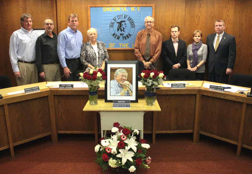 This evening's Oneonta Common Council meeting, the first since Mayor Dick Miller's passing, began with a moment of silence amid a tribute set up in his memory. From left are Council members Chip Holmes and Bob Brzozowski; Russ Southard, the new mayor; and Council members Madolyn Palmer, Larry Malone, David Rissberger, Maureen Hennessy and Mike Lynch. (Ian Austin/allotsego.com)