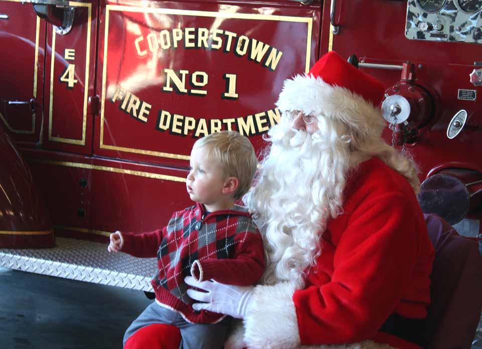 Henry Panny, 1, son of Chris and Connie Panny, Worcester, is among dozens of youngsters at the Cooperstown Fire Hall on Chestnut Street. Until 4 p.m., the firefighters are hosting games and goodies to help future firefighters celebrate the season.  (Jim Kevlin/allotsego.com)