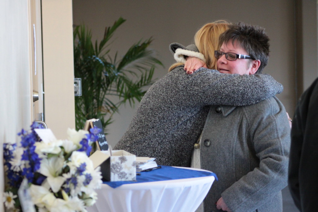 Friends and family of the late Kellie Place gathered in the Foothills Atrium where a memorial service was held Sunday afternoon. Here, after writing memories of Kellie for the family, Johnna Peachin embraces her friend Rachel Jessup in mourning.