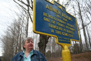 Deb Mackenzie examines Revolutionary War veteran Abner Adams' marker in one of her favorite historic resting places.  (allotsego.com)