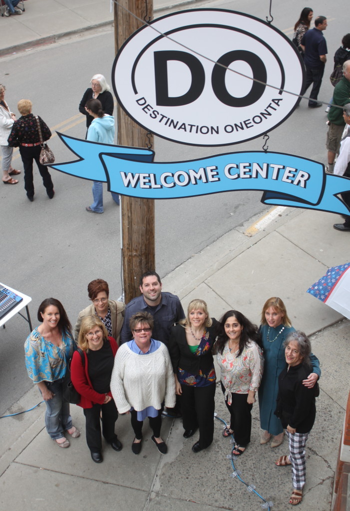 The first Fabulous First Friday of 2015 returned to Oneonta, with the opening of the new Destination Oneonta office at 2 Dietz St. Here, D.O. board members Julia Goff, Nancy Scanlon, Colleen Brannan, Rachel Jessup, Tim Masterjohn, Kristen Oehl, Louisa Montanti, Caroline Lewis and Sophie Richardson pose for a group photo beneath the new sign (Ian Austin/ allotsego.com)