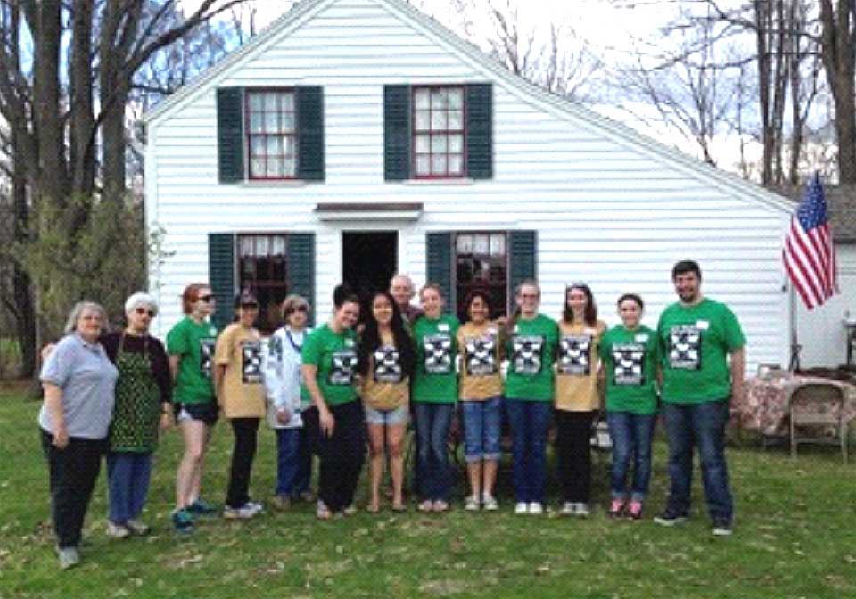 The spring cleaning done, volunteers -- including a contingent from SUNY Oneonta's "Into the Streets" service program – pose outside Oneonta's Swart-Wilcox House, the city's oldest surviving home that is now a house museum.  (Photo courtesy Helen Rees)