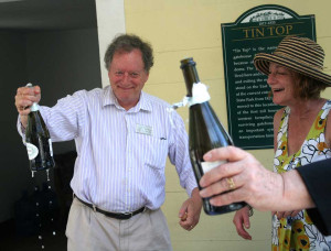Gary Koutnik, a Hyde Hall docent (and county board member from Oneonta), pops the cork for a champagne toast that followed the Tin Top ribbon cutting.  At right is Stacey Michaels, director of operations.
