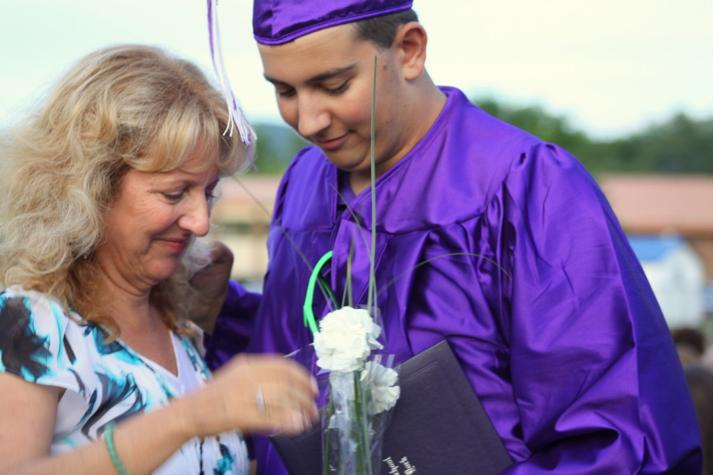 Brian Atwell gives his mother, Kathy, hugs and flowers after receiving his diploma at the Milford High School graduation on Friday, June 26.  The warm evening weather meant commencement could be held on the field for the first time since 2000. (Libby Cudmore/allotsego.com)