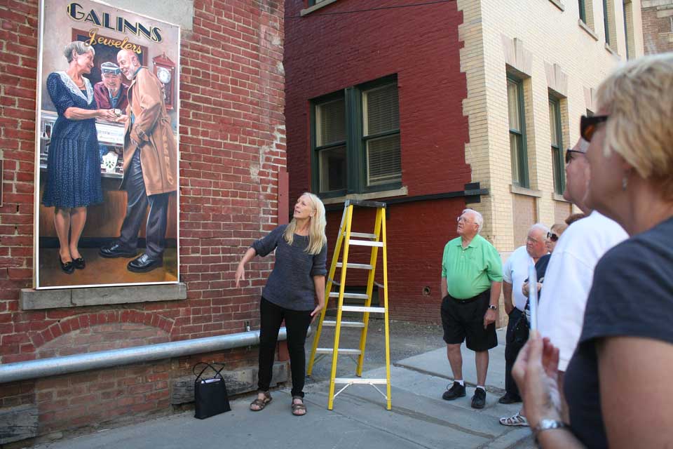 At 6 this evening, artist Carol Mandigo unveils the first of four murals planned on the Dietz Street wall of the Oneonta History Center, depicting the tenants who have occupied the downtown's first brick commercial block in the past century and a half. She collaborated with muralist Frank Anthony of Hamden. This mural depicts Galinns Jewelry, the last tenant. The second, to be unveiled next month, recreates the era when the building housed Wilber Bank. (Jim Kevlin/allotsego.com)