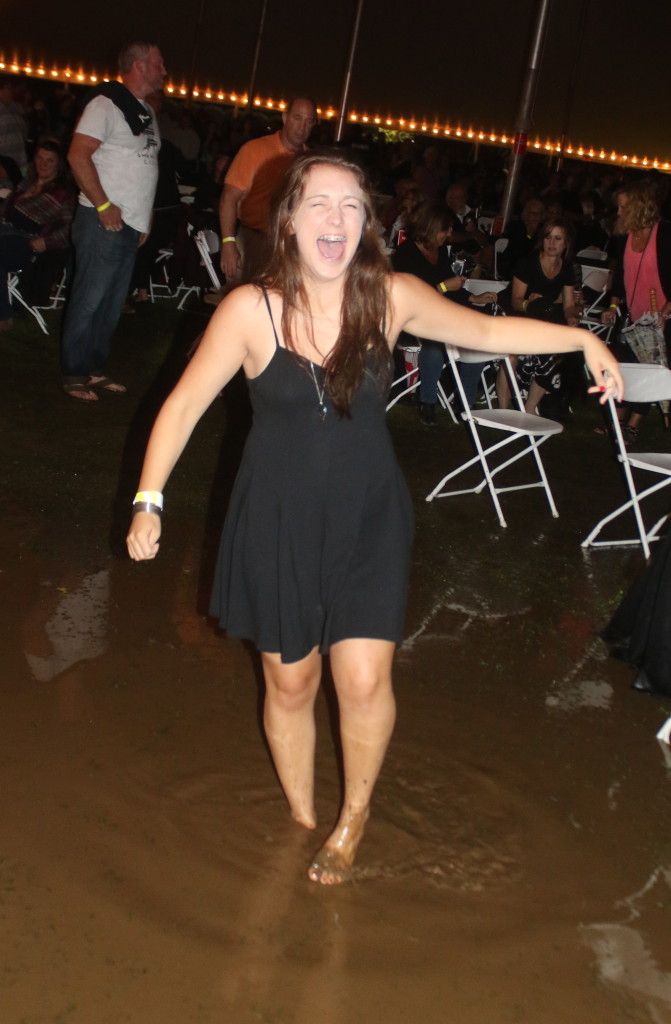 Erin Lutz, South Kortright, laughs as her shoe is sucked off in the ankle deep mud inside the concert tent. (Ian Austin/ allotsego.com)