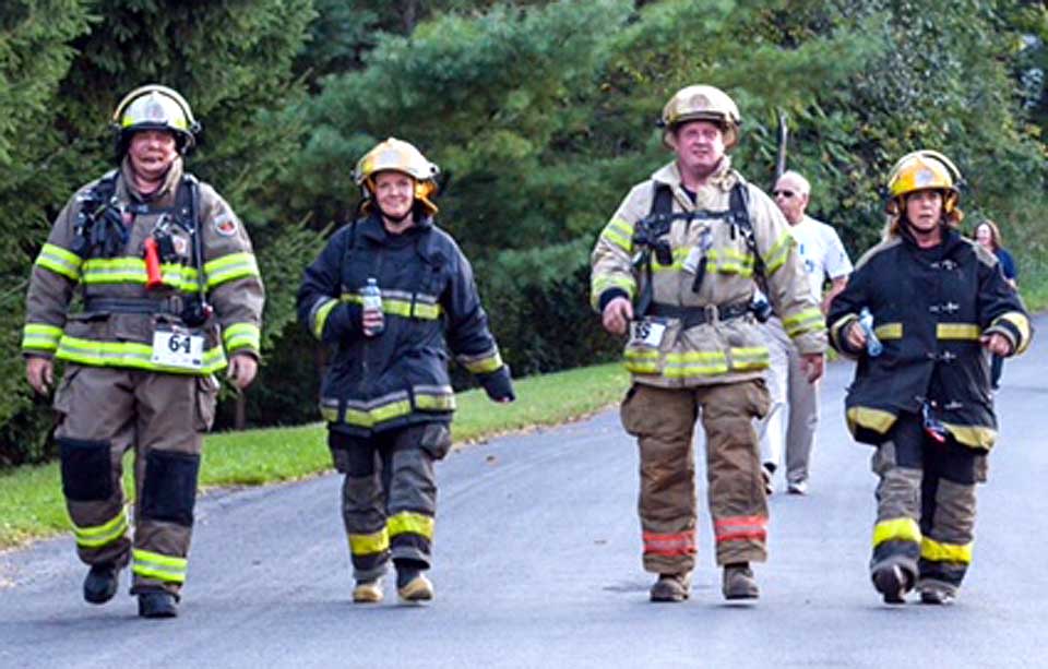 Four members of the Fly Creek Volunteer Fire Department completed the 9/11 Heroes 5K in full regalia. Approaching the finish line in Friday evening’s race are, from left, First Assistant Chief Steve Baker, Fire Company president Christine Voulo, Fire Chief Mike Thayer and EMS Jennie Johannesen. (Brittany LeSavoy photo)