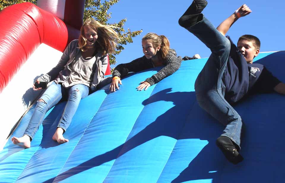 A big inflatable slide was one of Cooptoberfest's popular attractions, experienced here by, from left, Bella Jones, Riley Jubar and Chris Vuolo.