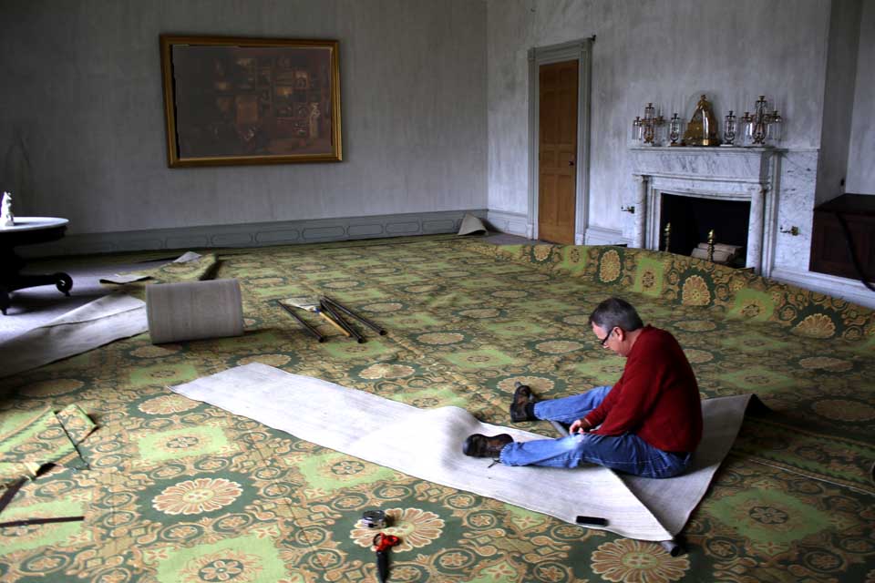 David Hunt and his wife, Charlene, proprietors of Vermont Custom Rug, Bristol, Vt., are installing a newly woven Brussels carpet in the drawing room at the Hyde Hall National Historic Landmark today and Friday. Through the extensive Hyde Hall archive at Cornell, the couple learned Lowe & Connach of New York City did the original carpet in 1831. While no record of the pattern or color remains, the Hunts created patterns that echo moldings on the ceiling and around the doors, and used color – green, chartreuse and gold – that had been used in the original furnishings. David said it was the style when George Hyde Clarke ordered the original carpet to decorate rooms with harmonious colors. The original family dining room and main staircase have already been covered with Damask carpet from Thistle Hill Weavers, Cherry Valley, and Hyde Hall Executive Director Jon Maney said the intent is to carpet the main diningroom and entrance hall next. (Jim Kevlin/AllOTSEEGO.com)