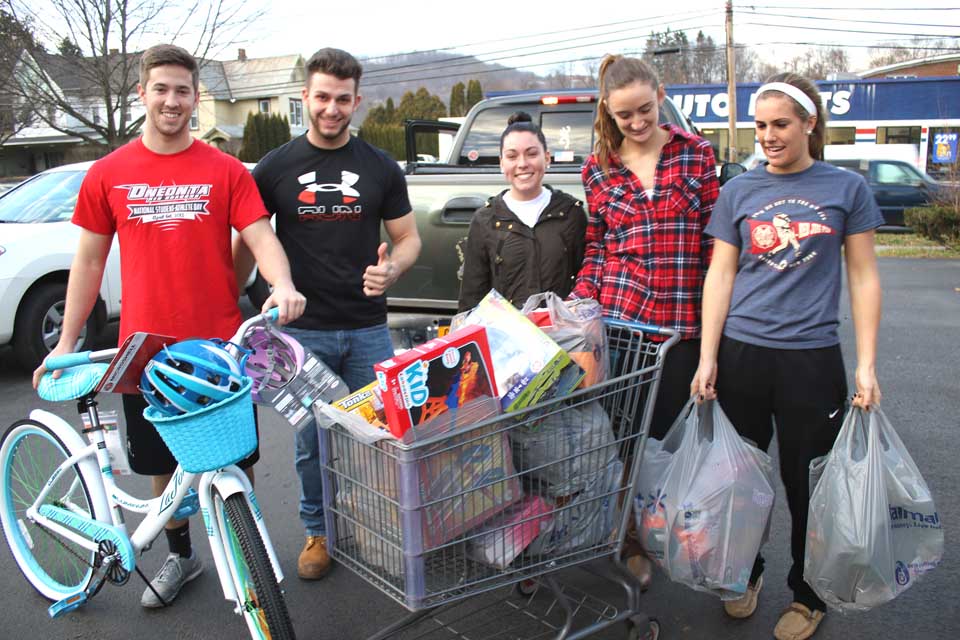 SUNY Oneonta's Santacon raised $10,000 this year, and organizers – from right, Meaghan Foster, Cassandra Kohler and Ceili McMorrow – spent half on presents for Toys for Tots, and the other half on toys for the Salvation Army's Angel Tree program. Helping the three organizers deliver the toys to the Salvation Army's River Street post this afternoon were Sam Beaulac, left and Jack Sangalli. (Jim Kevlin/AllOTSEGO.com)