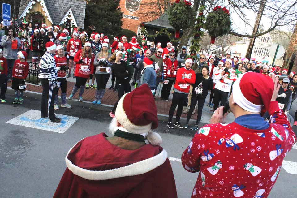 Cooperstown Chamber Executive Director Matt Hazzard, in what he's calling his Christmas one-sie, instructs 110 runners about to vie the second annual Ugly Sweater Run/Walk. With welcoming temperatures in the 50s, that's up from 30-some last year, when an ice storm delayed the inaugural event for a year. CCS track standout Scott Curtis won the 4K in 23:12. Sakiko Yamagata of Brooklyn won the 2K. (Jim Kevlin/AllOTSEGO.com)