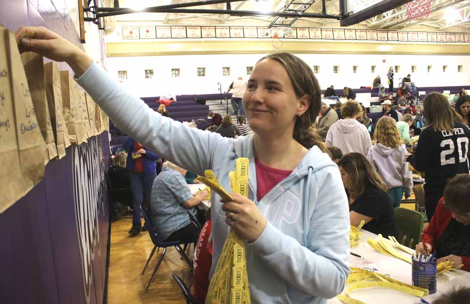 An hour into today's Chinese auction to benefit the Goodyear Lake Polar Bear Jump the crowd was still lined up down the hall from the Milford Central School gym to the door, waiting to buy tickets by the fistful and take a chance at getting a bargain on hundreds of donated items. In top photo, Lydia Garlick of Milford puts a ticket in one of the bags that lined the walls. At right, Laurie Burch of Milford and her grandson, Michael Virtell, queue up to buy their tickets. This year's Polar Bear Jump, the 21st, is Saturday, Feb. 20. (JIm Kevlin/AllOTSEGO.com)