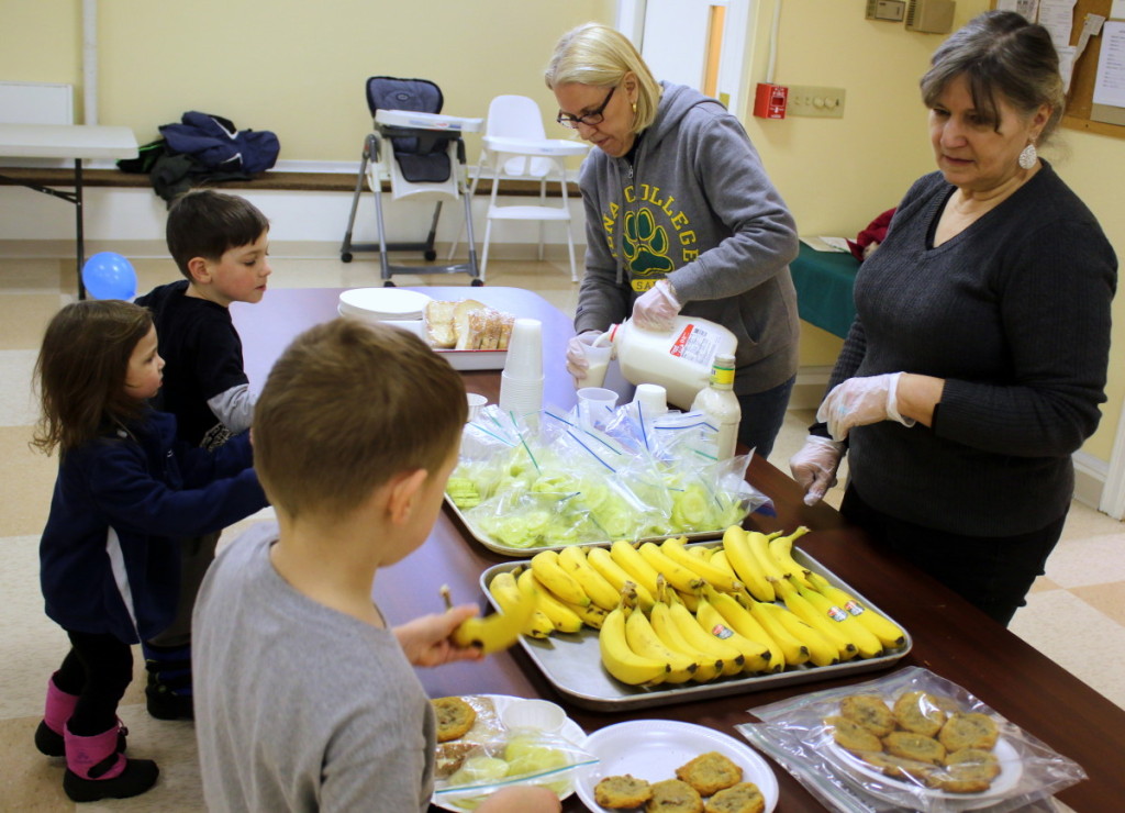 Got hungry kids? Send them down to the First United Presbyterian church across from Friendly's for a free lunch at the Winter Lunch Party! Here, Oneonta siblings Chris, Abigal and Ben Johnston saddle up to the table of the Winter Lunch Party for a free lunch of ham and cheese sandwich, cucumbers, bananas, milk and a cookie, served by Rebecca LaBarr and Nadine Stenson. The program offers free lunches and crafts to children up to 19 and runs Monday through Friday, 11:30-12:30pm through winter break. (Ian Austin/AllOTSEGO.com)