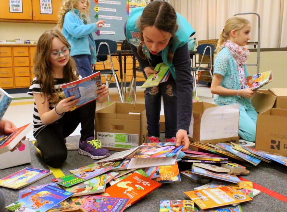 Caitlin Wiltsey, Maria Griswold and Kara Piefer of Girl Scouts troop 30043, sort through 1,438 donated childrens' books they collected for the Bookcase for Every Child project headed by Tenfold Plus. The books were then counted and organized into boxes. (Ian Austin/AllOTSEGO.com)