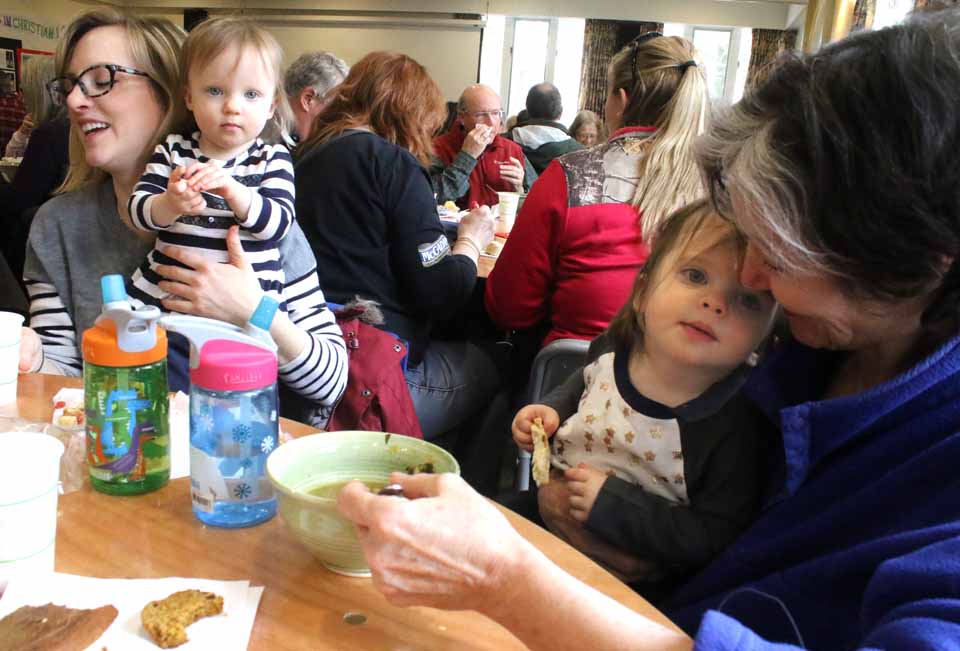 Grandmom Betsy Foster, right, and mom Flannery Foster share soup with twins Mira, left, and Rosalie Foster, 16 months, and today's Empty Bowls benefit luncheon underway until 2 p.m. at the Christ Episcopal Church Hall, Fair Street, Cooperstown. There were fears the two CCS basketball quarter-finals in Whitesboro this afternoon would divert soup-eaters, but – instead – a number of people said they were fueling up for the trip north. (JIm Kevlin/AllOTSEGO.com)