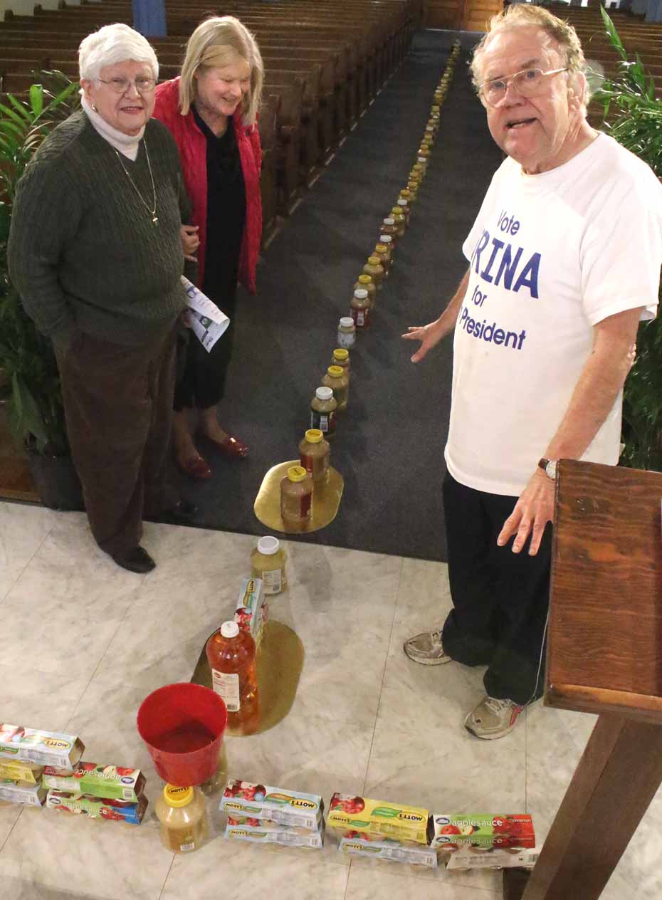 Parishioners at St. Mary’s “Our Lady of the Lake” Catholic Church in Cooperstown had added a twist to their annual Lenten food collection for the needy. Using 40 jars (one for each day of Lent) of apple sauce (a food that all ages partake of), the parish has created a cross on the template of the central aisle and the transept. Also this year, the Lenten collection has expanded to include personal-care items for the “food insecure,” and diapers and other supplies and toys for infants. Here, Father John P. Rosson, pastor, discusses transporting the supplies to the Cooperstown Food Bank with parishioner Kathy Raddatz and Maureen Brennan, parish office secretary. Donations are being accepted until Sunday. (Jim Kevlin/AllOTSEGO.com)