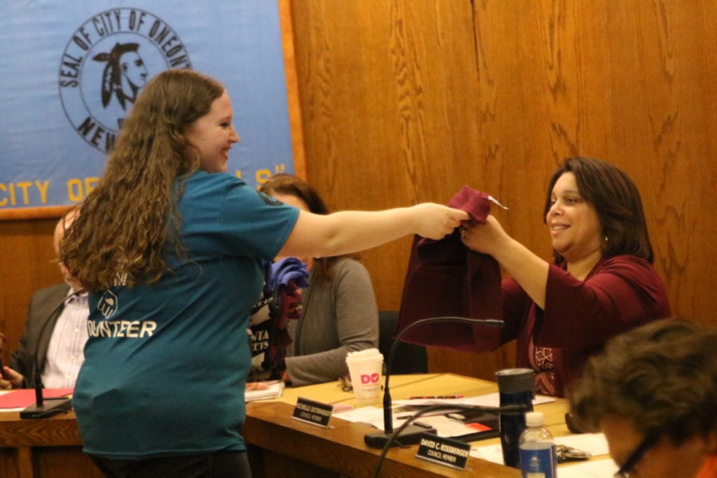 SUNY's Jessica Levy, student coordinator for Into The Streets, hands an event tee shirts to Michelle Osterhoudt before the start of the Common Council meeting this evening. Levy invited council to join the volunteer efforts alongside students in cleaning up downtown on April 30th. Council members Michelle Osterhoudt, Joe Ficano, John Rafter and Melissa Nicosia accepted. "When I came to school here, I wanted Oneonta to to feel like a community to me." said Levy. "I was able to get that through volunteering. I love it so much I want to share that love with you all." Mayor Gary Herzig went on to commend Levy, saying "We love having you here and are so appreciative of your work." (Ian Austin/AllOTSEGO.com)