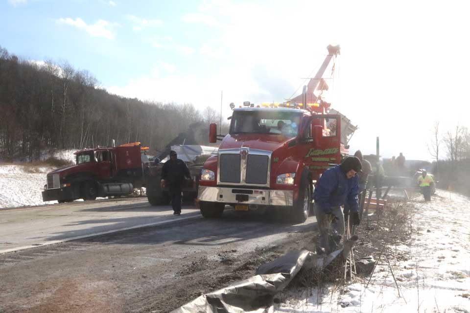 A tow-truck operator removes debris from I-88 while trying to untangle three tractor-trailers from a Trailways Bus in Sunday's crash. (AllOTSEGO.com)