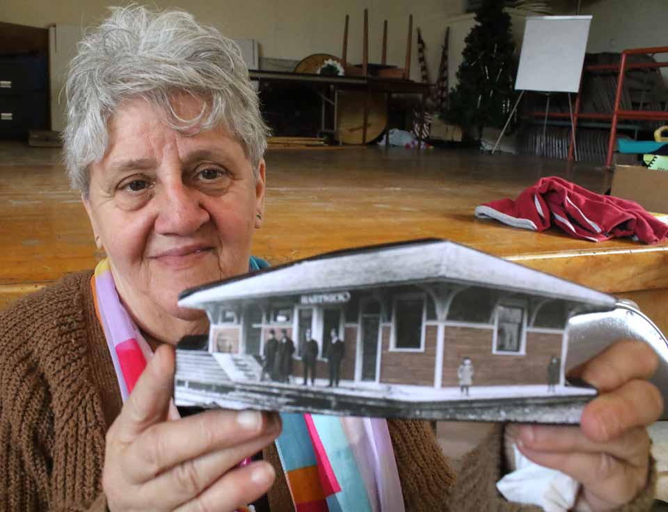 "Partners in Preservation," and second annual history fair organized by OCHA, the Otsego County Historical Association, attracted 22 historical societies that set up booths in the Springfield Community Center. New this year were Otego, Gilbertsville and Roseboom. In top photo, Caren Kelsey, president of the Hartwick society, holds up a depiction of the old depot in Hartwick hamlet that is being sold this year as a fundraiser; upcoming projects include raising money to bring the gazebo in the hamlet back to its original condition. At right, Ellen LaSalle, Cherry Valley, considers a copy of Al Bullard's "The Hop Farmer’s Year," published last fall OCHA President Deb Mackenzie, Hartwick, said the society's first countywide fair was last year in Cooperstown and addresses OCHA's central mission: To get local historians communicating with each other. Currently, the historians are working together (with the county Department of Planning, Solid Waste & Economic Development) to update and computerize a cemetery map first assembled by Butternut Town Historian Leigh Eckmair. (Jim Kevlin/AllOTSEGO.com)