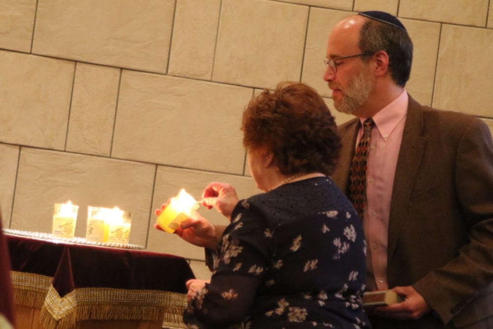 Ken Sider, President of Temple Beth El in Oneonta, lights a ceremonial candle alongside Regina Betts, a Holocaust survivor, during a Holocaust Martyrs' and Heroes' Remembrance service this evening at the synagogue. Six candles were lit for the 6 million who died. (Ian Austin/AllOTSEGO.com)