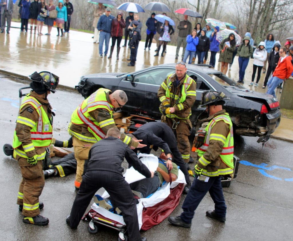 Rain only added to the sinking feeling of unease as Hartwick students observed a mock-drunk driving accident featuring students, Grummons Funeral Home and members of the Oneonta Police and Fire Departments. Here, firefighters Captain Brad Smith, Mark DeGraw, Erik Johnson and Assistant Chief Jim Maloney work with Stephen Fournier and Ryan Walsh of Grummon's Funeral Home, load the 
