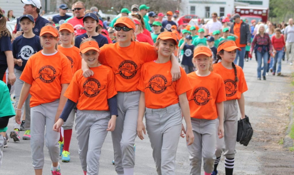 Nothing marks the beginning of summer like the Cooperstown Youth Baseball parade in Hartwick. Here, the girls of the Hartwick American Legion team Braeden Victory, Hannah Craig, Lauren Koffer, Madison Hayes, Elianna Geertnes, Jeana Geertnes and Ava Caporali walk with other teams to the opening ceremony at the Beanie field in Hartwick. (Ian Austin/AllOTSEGO.com)