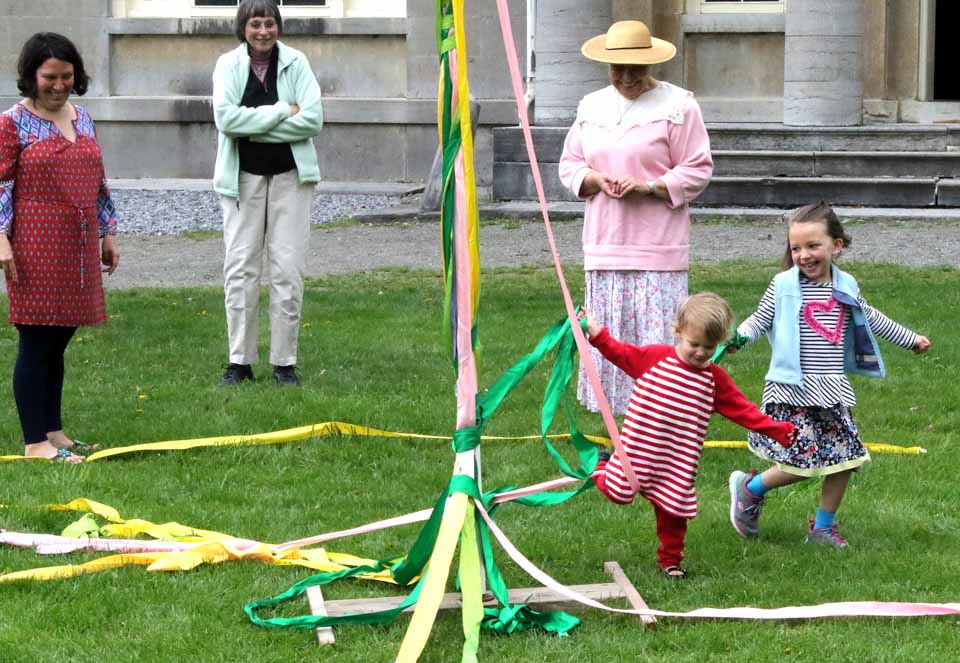 Hundreds of moms (and dads), their children, and just children, young and old, were drawn to Hyde Hall on Otsego Lake today for the National Historic Landmark mansion its increasing popular Mother's Day Weekend festivities.  Above, the Koehn sisters of Oneonta, Adella, 5, and Annika, 3, lace a Maypole, directed by volunteer Mary Margaret Kuhn (in straw hat).  Mom Jenny, left, (as well as brother Alden, 3), helped, as grandmom Aleda Koehn, looked on.  At right, Rick Scheiner of Westford brought mom Barb Schein, of Westford and Newport News,Va., to visit the mansion after attending the Worcester Library benefit luncheon at The Otesaga.  (Jim Kevlin/AllOTSEGO.com)