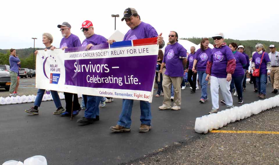 Holding the banner at today's Cooperstown/Northern Otsego Relay For life are, from right, survivors Ed Bellow and Jim Domion, both of Richfield Springs, and Michael Hall, West Oneonta. At the far end is Helen Gregory, executive director of the local chapter of the American Cancer Society. The Relay continues until 10 p.m. at Cooperstown Dreams Park in Hartwick Seminary. (Jim Kevlin/AllOTSEGO.com)