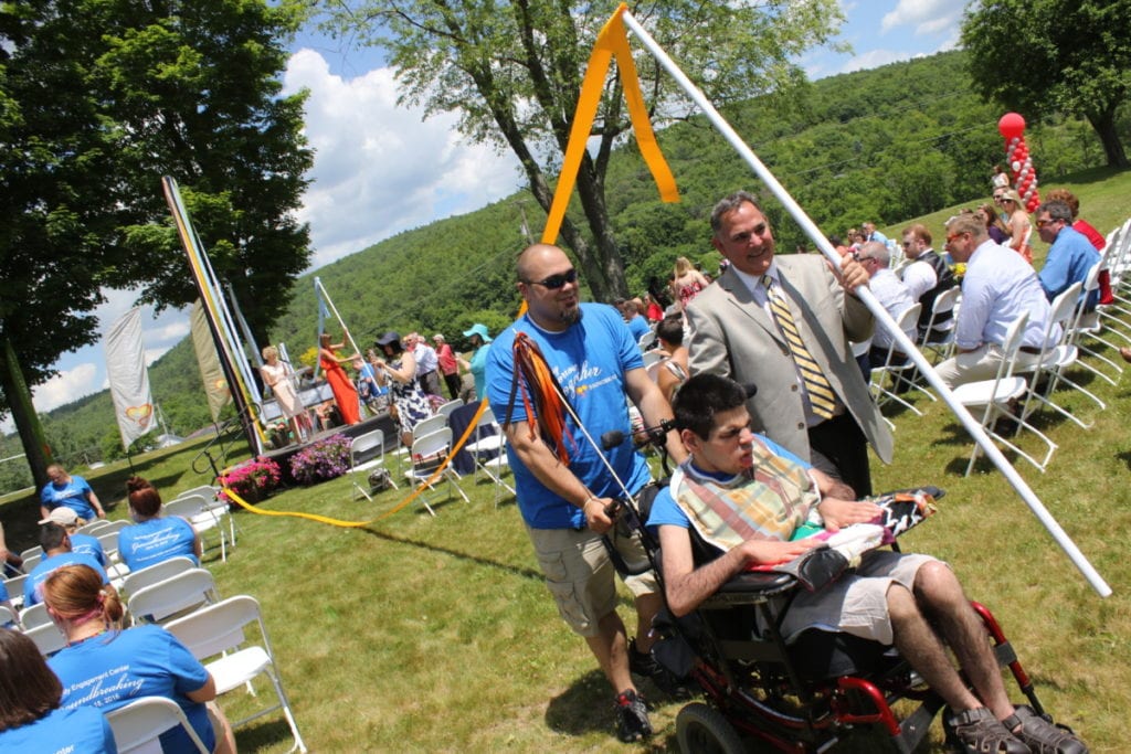 In the "groundbreaking" of the Family Engagement Center at Springbrook, Jerry Pondolfino, right, son Zach and Assistant house manager Matt Love, carry one of several ribbons which were stretched out to show where the new building will stand when it is completed in 2017. (Ian Austin/AllOTSEGO.com)