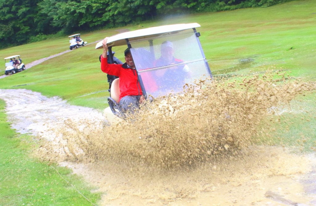 Fred Schneider, Cooperstown, drives through a puddle on the Colonial Ridge Golf Course while partner Sean Campbell holds on for dear life. But despite the storm that delayed tee-off time two hours, the game worth the wait, part of the Friends Helping Friends benefit tournament to raise money for for cancer patients Art Boden and David Selover. (Ian Austin/AllOTSEGO.com)