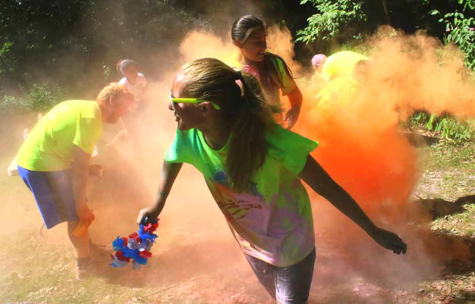 Montana Miller and Elizabeth Cleveland, Oneonta, emerge from a cloud of orange smoke as they pass a color station in the 1st LEAF color Run, held throughout Neawah Park this morning before the parade.