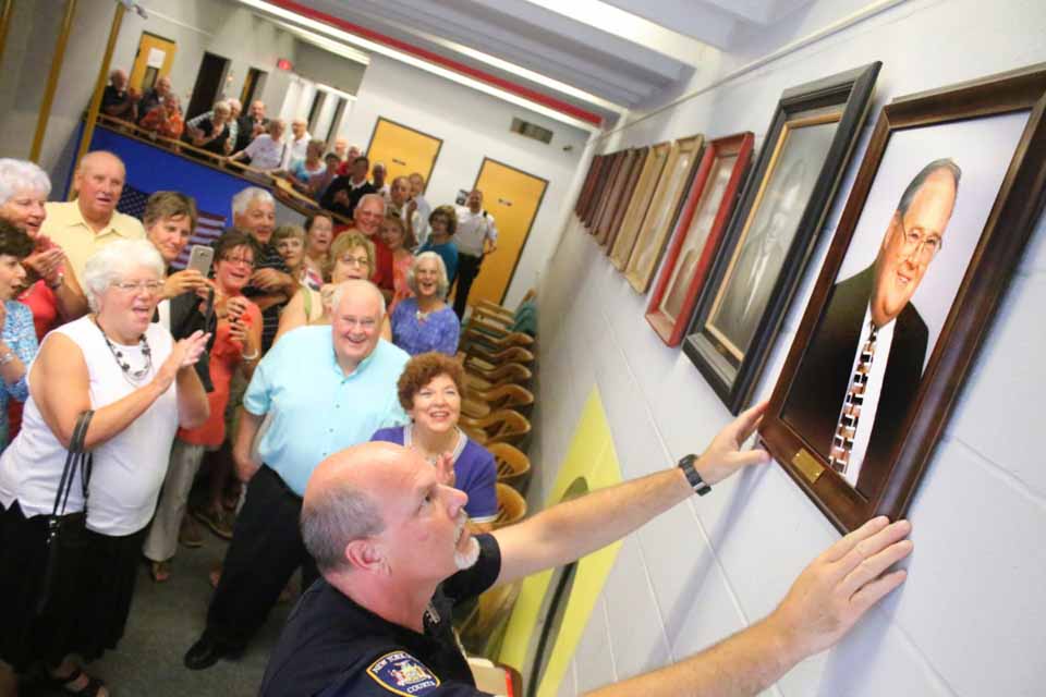 State Court Officer Matthew Brown hangs the official portrait of former Oneonta City Judge Walter Terry III, seen behind him with wife Diane, in the City Court hallway this afternoon in the city's Public Safety Complex at Main and Market.   Family and friends attended to celebrate the event. County Judge Brian Burns, City Judges Richard McVinney and Lucy Bernier and Chief City Courty Clerk Cathy Tisenchek delivered remarks praising Judge Terry's character, ethics, respect, fairness and temperament.  Judge Terry served on the city bench from 1999 to 2008, then resumed private practice. (Ian Austin/AllOTSEGO.com)