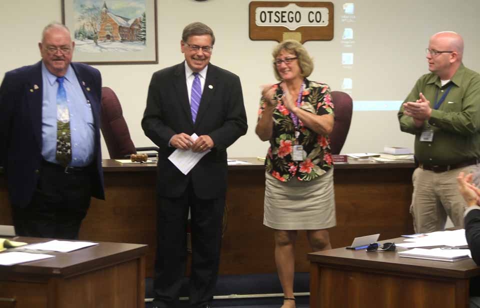 To applause, state Sen. Jim Seward, R-Milford, accompanied by Assemblyman Bill Magee, D-Nelson, announce a $1 million grant – half from the Senate, half from the House – to help complete the 12-tower emergency communication system due for completion this fall. The state legislators appeared before the county Board of Representatives of its monthly meeting in Cooperstown. Among those applauding are, right, county 911 Director Rob O'Brien, and, next to him county Board Chair Kathy Clark, R-Otego. (Jim Kevlin/AllOTSEGO.com)