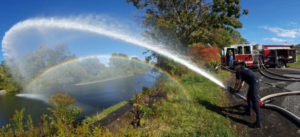 Erik Johnson of the Oneonta Fire Dept. adjusts the spray on a water flow monitor to make a rainbow over the Southside dam this afternoon. Johnson was one of several firefighters at the site testing the water pump output with 10 and 20 ft hoses to make sure the capacity inside the truck is up to standards. The test is preformed annually. (Austin/AllOTSEGO.com)