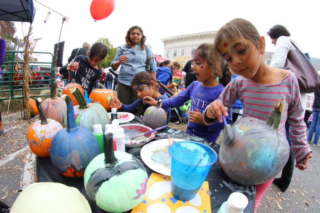 Cooptober Fest was filled with children's activities including bounce houses, face painting, carnival games, painting, train rides and more! Here, Bijal Patel, top, Cooperstown watches her daughter Maya, niece Arya, daughter Mira and niece Avni paint pumpkins at the Cooperstown Lions Club tent. (Ian Austin/AllOTSEGO.com)