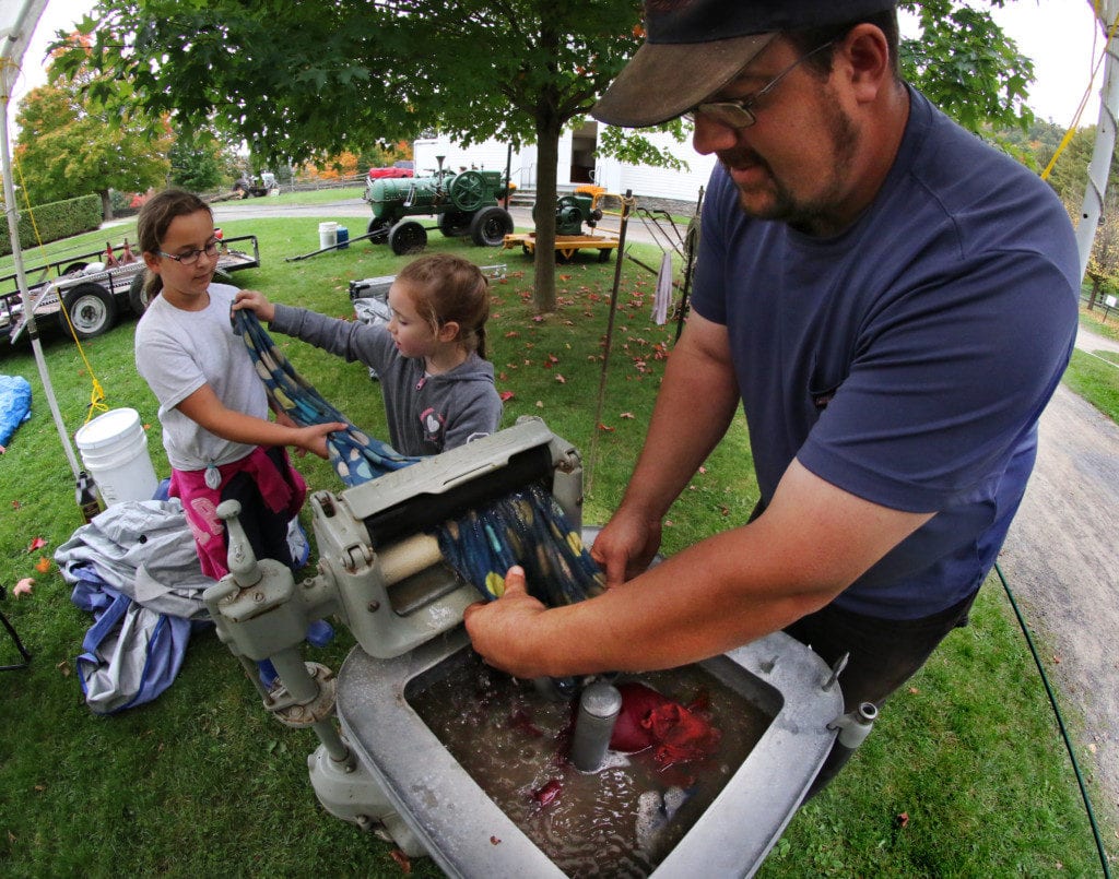 Mike Stevens, Oneonta, enlists the help of his daughters Victoria and Alicia in demonstrating a 1927 Maytag washing machine on display at Tractor Fest at The Farmer's Museum this afternoon. In addition to many antique tractors on display, families can see old fashion hay threshing, try roasted corn, explore the historic village, pet animals and more! The fun continues Sunday 10-5pm. The event funds scholarships for New York college freshmen pursuing careers in agriculture. (Ian Austin/AllOTSEGO.com)
