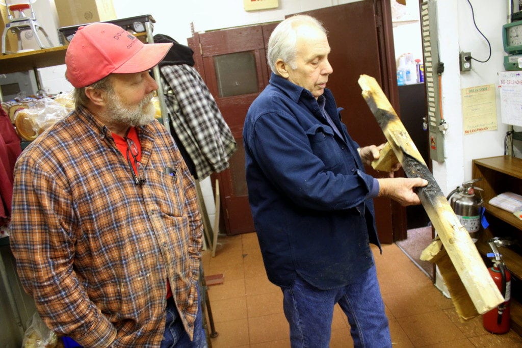 Dick Morey, right, Oneonta, owner of Morey's Family Restaurant, shows Rich Dennis of Double D Contracting a piece of scorched wood removed from the wall yesterday after employees put out a small fire in the outer wall. (Ian Austin/AllOTSEGO.com)