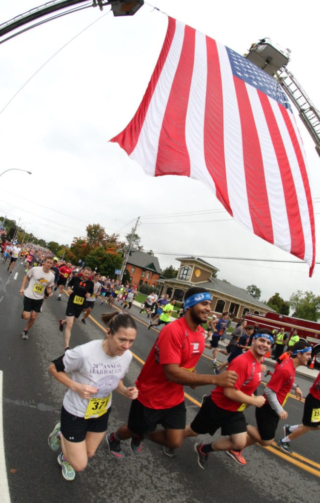 In front, Nicole Vanhoesen, Elbridge, and members of the SUNY Oneonta Wrestling team James Bethel, Andrew Werther, Dakota Inman and Nicholas Heck take off beneath the American flag at at the start of the 23rd annual PIT run this morning. Also pictured are Robb Munro, Delhi, and Ryan Keator, Delhi. (Ian Austin/AllOTSEGO.com)