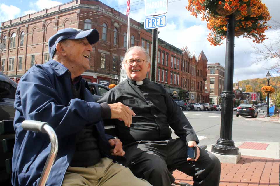 The chaplain of the U.S. House of Representatives, Father Patrick J. Conroy, S.J., chats with Joe Russo, Mickey's Place owner Vin Russo's dad, at "the flagpole" in downtown Cooperstown a few minutes ago. Father Conroy is filling in at St. Mary's "Our Lady of the Lake" Catholic Church, while the pastor, Father John P. Rosson, is on vacation in Williamsburg. Father Conroy arrived in the village last evening, and said dailyl mass this morning at Focus Rehab in Index. He will be celebrating daily and weekend masses at the Elm Street Church during his stay, and is looking forward to Saturday evening's Oktoberfest at St. Mary's Church Hall. (Jim Kevlin/AllOTSEGO.com) 