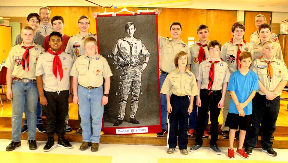 Members of Cooperstown Boy Scout Troop 1254 poses a few minutes ago with a newly completed quilt square commemoration Hank Nicols, a troop member who contracted the disease in the 1980s while receiving blood transfusions to treat his hemophilia. The square – 3 by 6 feet, the size of a coffin – is the second one completed by Hank's mother Joan. His father, also Hank, is a troop leader. The troop then watched "Eagle Scout: The Story of Henry Nicols," an HBO film recounting how the young man announced his diagnosis 25 years aog, then campaigned for AIDS awareness before succumbing to the disease in 2007. (Jim Kevlin/AllOTSEGO.com)